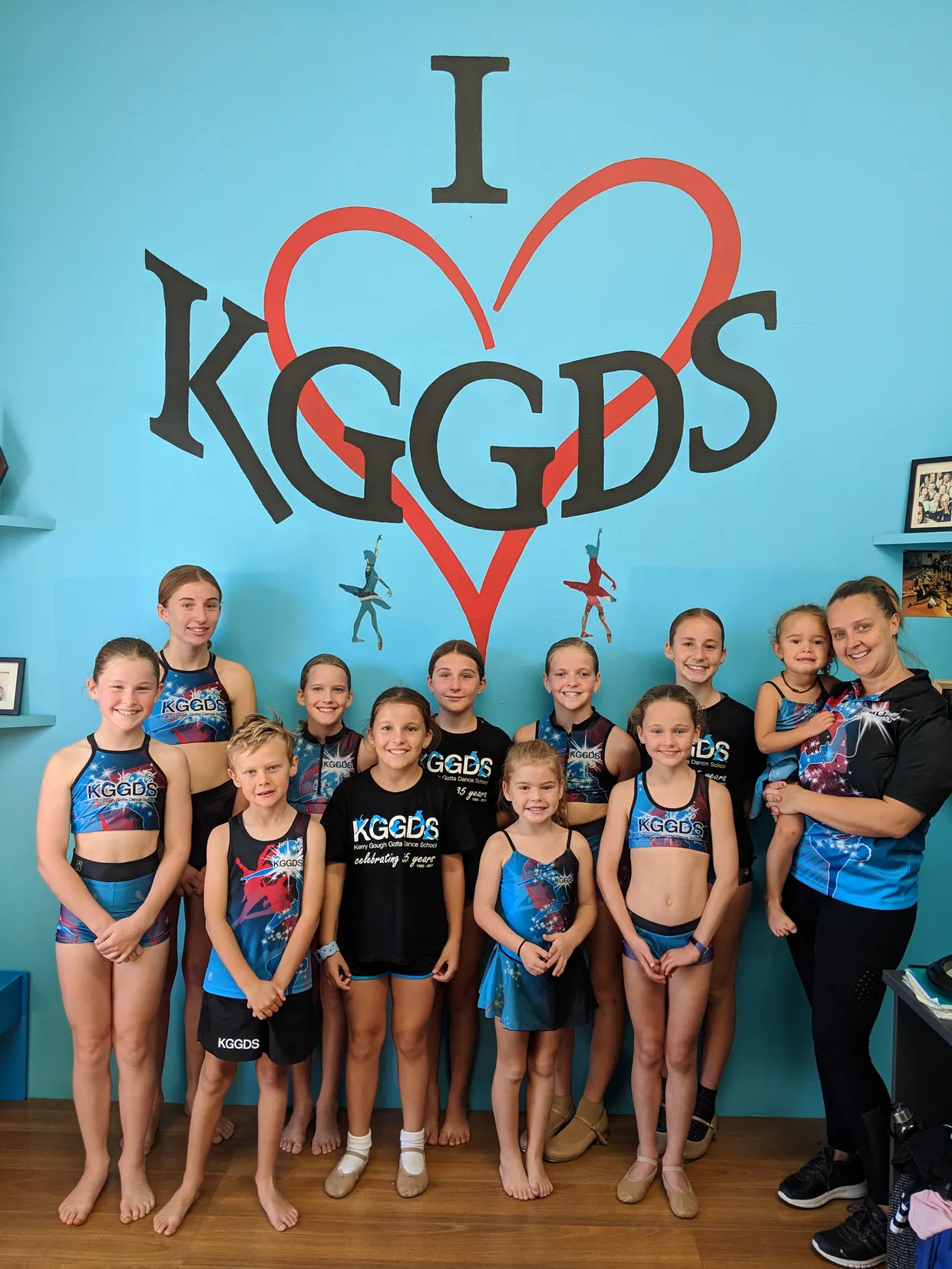 Group of KGGDS students and Teacher posing under KGGDS signage.